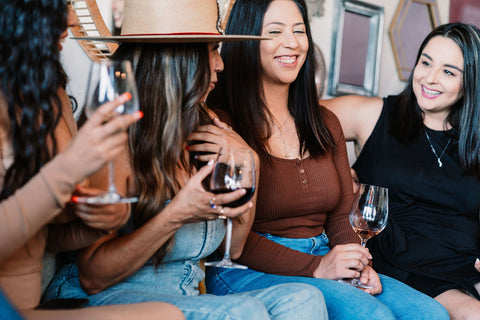 Four Latinas laughing and enjoying wine with wine glasses in their hands.